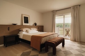 Una camera da letto con un letto, comodini, una panca, un quadro incorniciato e vista sull'esterno.