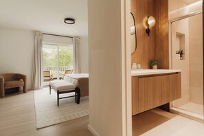 A modern bathroom with a wooden vanity, a mirror, and a shower area.