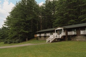 Un lodge su due piani con facciata in pietra, terrazza in legno e una scala che conduce al livello superiore.