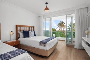 Een hotelkamer met een groot bed, een nachtkastje, een lamp en uitzicht op de oceaan.