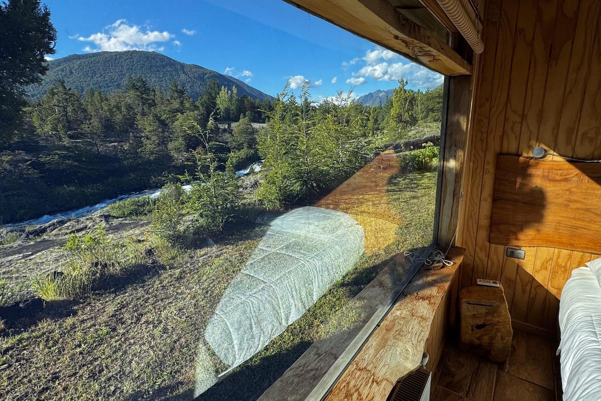 Una cabaña con vista a un valle boscoso y una montaña.