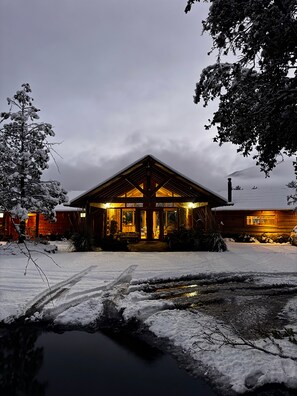 Une cabane en bois dotée d’un porche abrité, entourée d’un paysage enneigé et d’arbres.