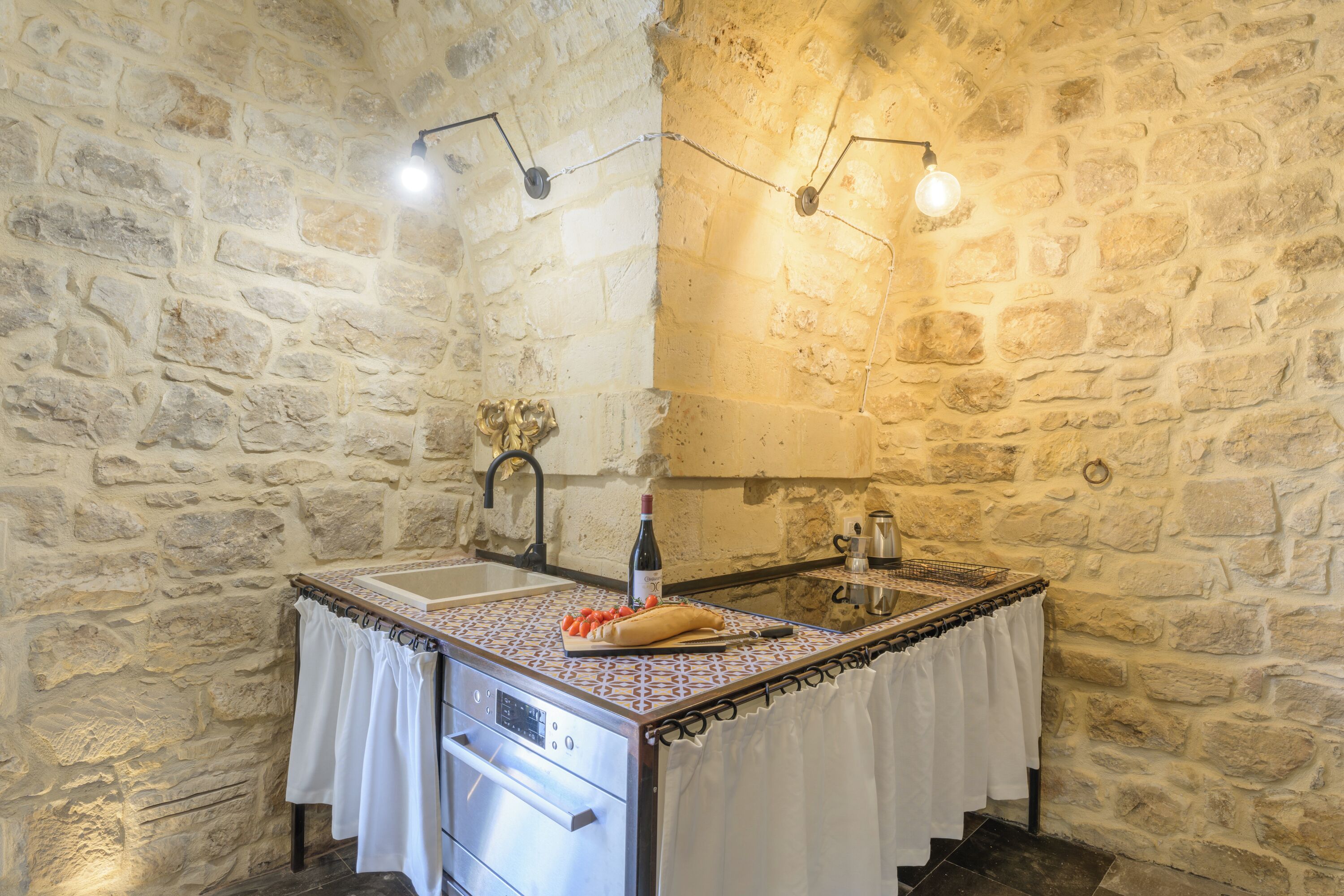 A stone-walled bathroom with a sink, mirror, and towel rack.