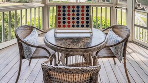 A covered outdoor area with a ceiling fan, wicker furniture, and a view of palm trees and buildings. - New Listing! Tidewater Ocean View! Steps from the Beach! Screened in Porch!  (Isle of Palms)