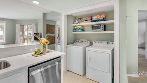 A compact kitchen with a dishwasher, two washing machines, and a built-in oven. - New Listing! Tidewater Ocean View! Steps from the Beach! Screened in Porch!  (Isle of Palms)