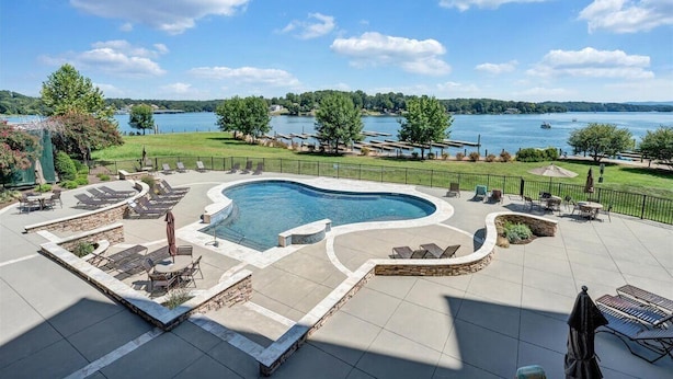 A pool area with a view of a lake, surrounded by lounge chairs and a stone deck. - Bridgewater Pointe (Westlake Corner)