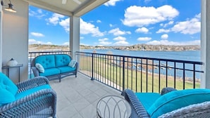 A covered balcony with wicker furniture and a view of a lake. - Bridgewater Pointe (Westlake Corner)
