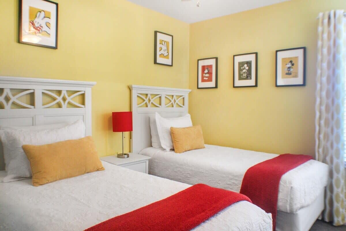 Habitació d'hotel amb dos llits, una làmpada vermella i quadres al mur.