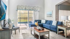 A modern living room with a blue sofa, a coffee table, and a TV on a stand.