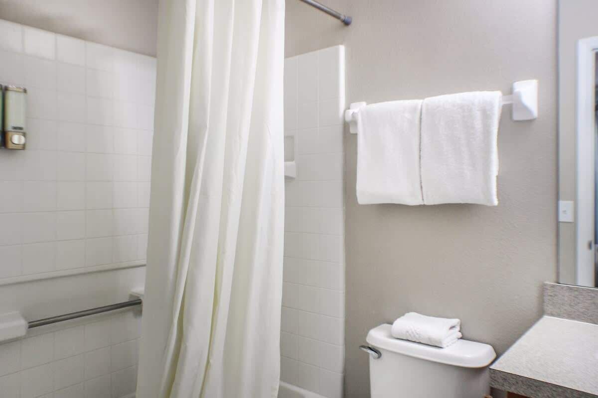 A bathroom with a shower curtain, a toilet, and a towel hanging on the wall.