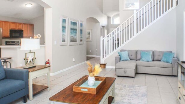 A spacious living area with a sofa, coffee table, and a staircase.
