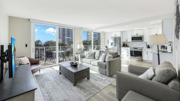 Un apartamento moderno con sala de estar, comedor y cocina. Cuenta con ventanas amplias, un balcón y vistas a la ciudad.