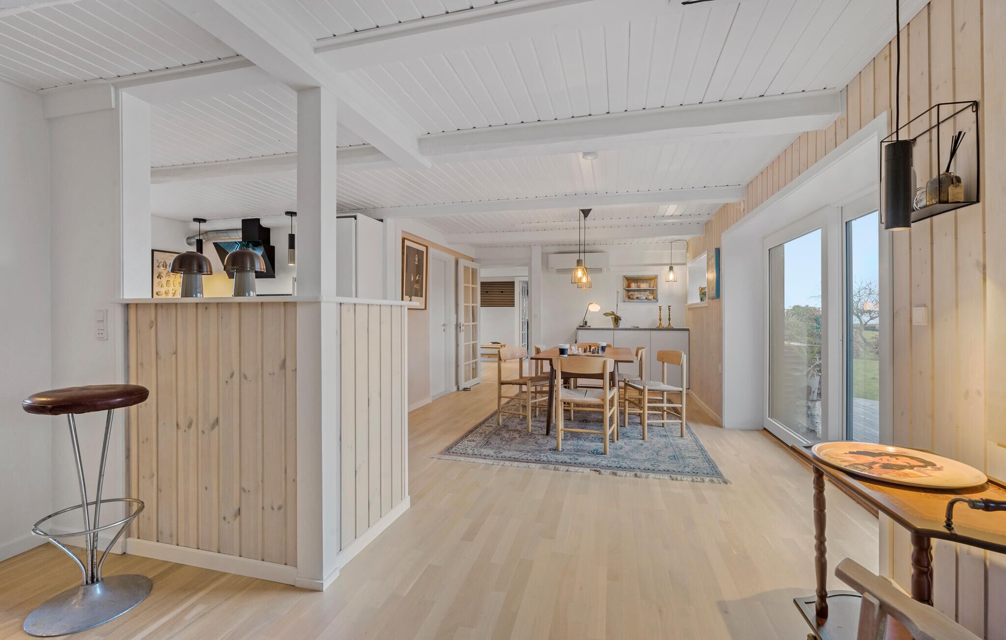 Et moderne køkken med trædetaljer, et spiseområde med et tæppe og en bar med barstole.