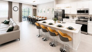 Una cucina moderna con mobili bianchi, elettrodomestici in acciaio inossidabile e un'isola centrale con sgabelli da bar.