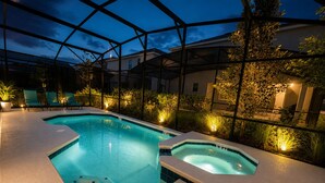 Una piscina con una vasca idromassaggio, circondata da lettini e piante, sotto una tettoia.