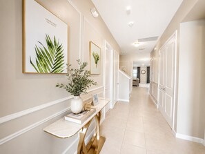 A hallway with a marble console table, framed botanical prints, and a potted plant.