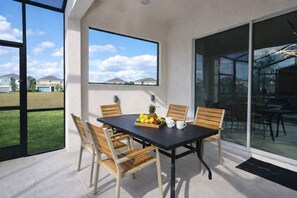 A patio with a table, chairs, and a fruit bowl.