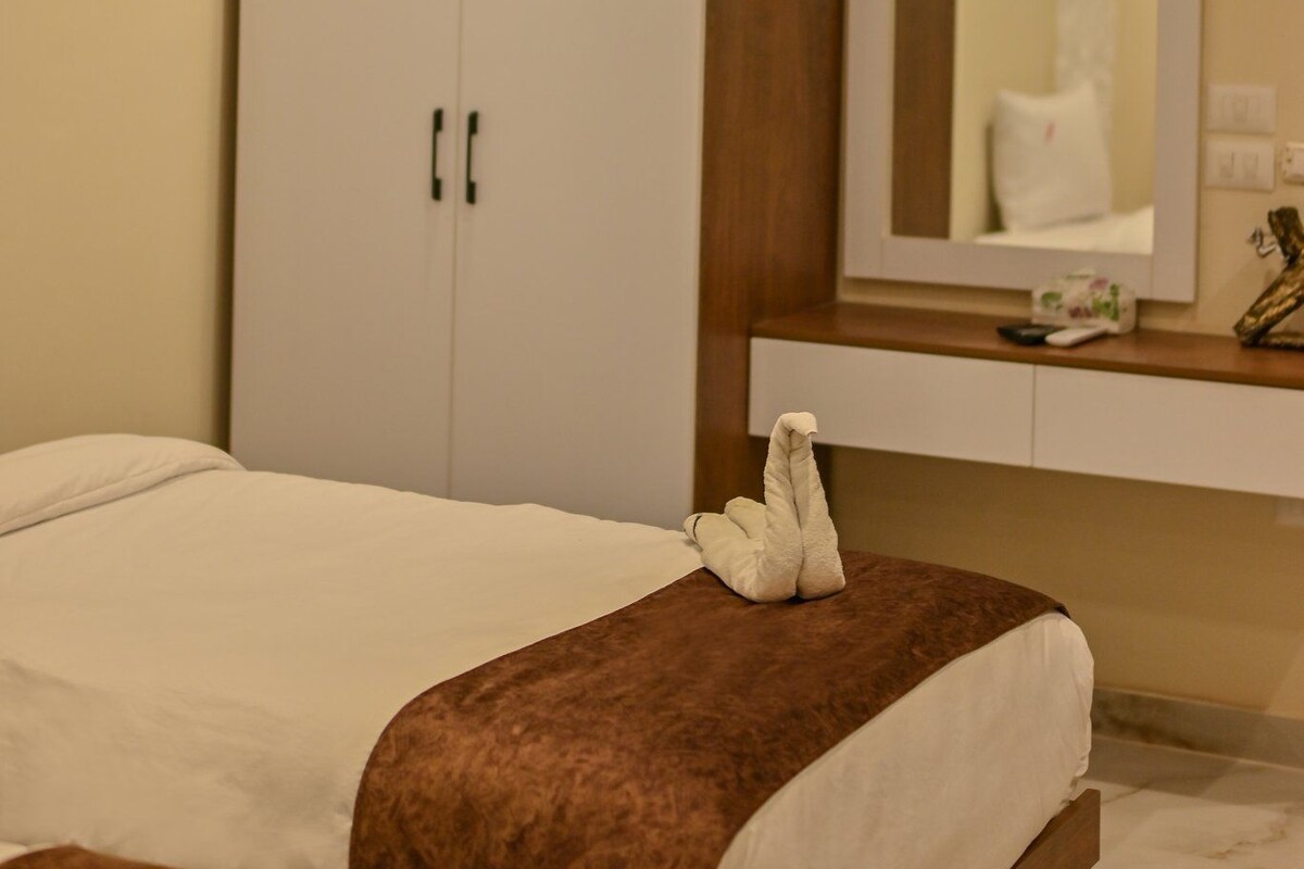 A hotel room with a bed, a wardrobe, a mirror, and a bedside table.