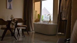 Un salon moderne doté d’une grande baignoire, d’un coin repas avec des chaises et offrant une vue sur la pyramide.
