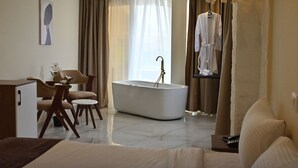 Une chambre d’hôtel moderne équipée d’une grande baignoire, d’un canapé, d’un bureau et d’une chaise.