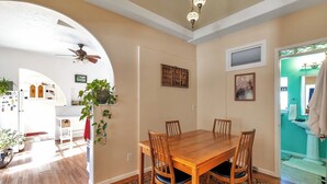 A dining area with a wooden table and chairs, a patterned rug, and a ceiling fan.