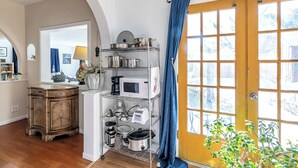 A kitchen with a wooden cabinet, a white refrigerator, and a metal rack holding kitchen utensils and appliances.