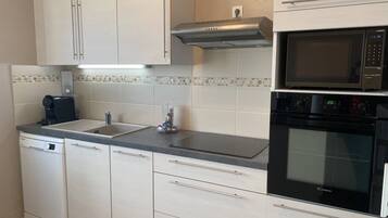 Een koelkast, een oven, een broodrooster, kookgerei, borden en bestek