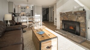 Ein geräumiges Wohnzimmer mit Kamin, Couchtisch aus Holz und einer Ledersofa.