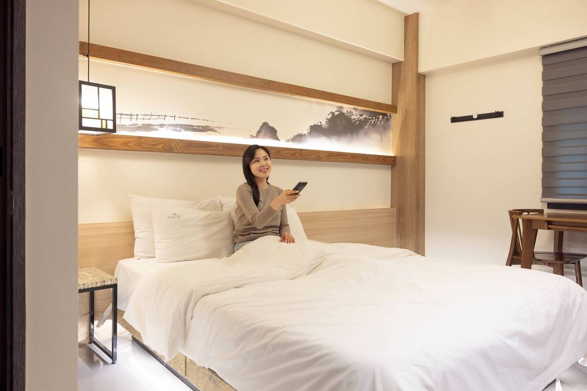 Une chambre d’hôtel avec un lit, un bureau et une étagère fixée au mur.