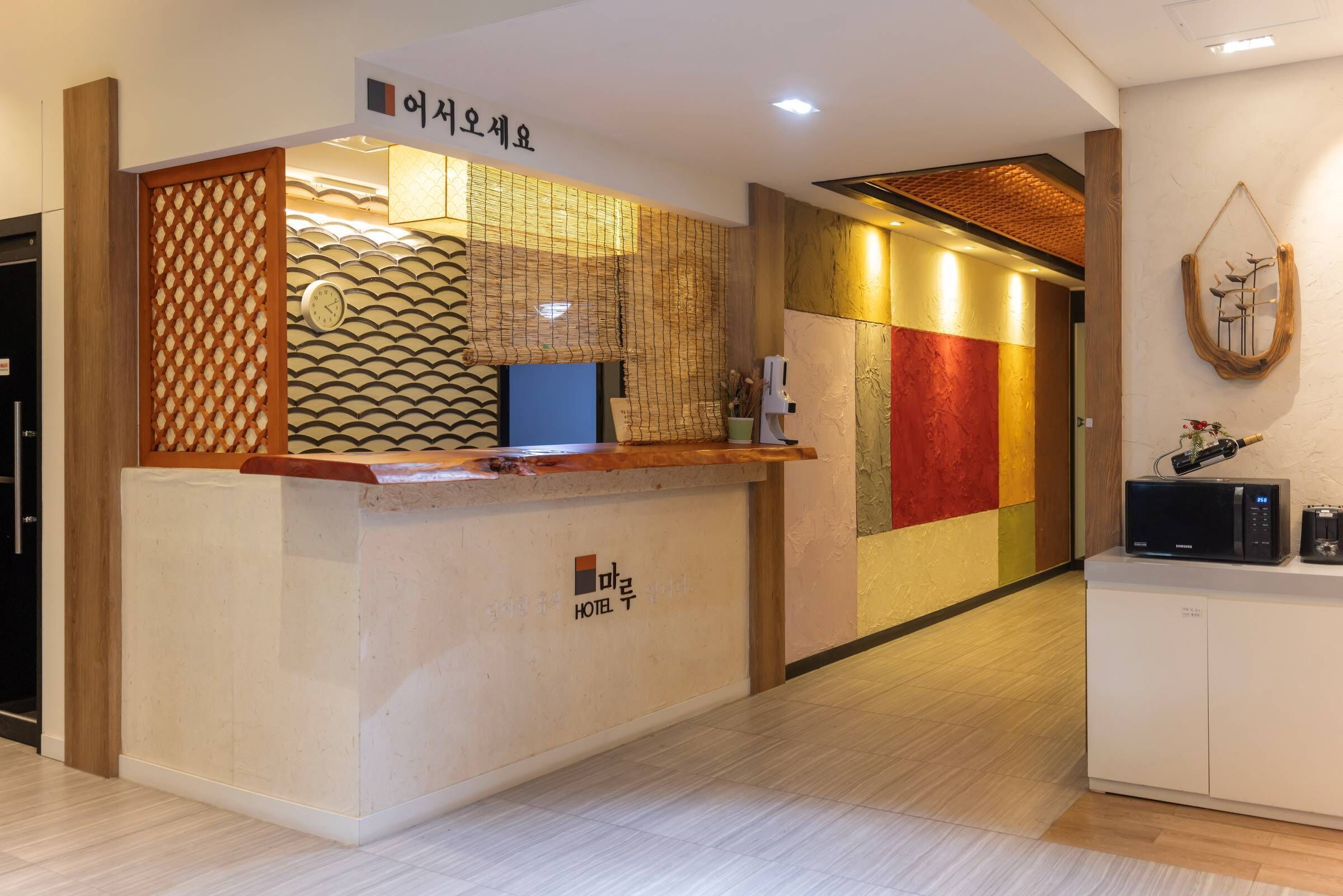 Una recepción de hotel con un diseño moderno, un reloj y un letrero en coreano.