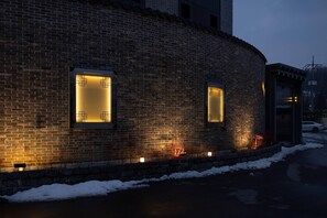 A brick building with illuminated windows and a snow-covered ground. - From H Maru Hotel Pocheon (Pocheon)