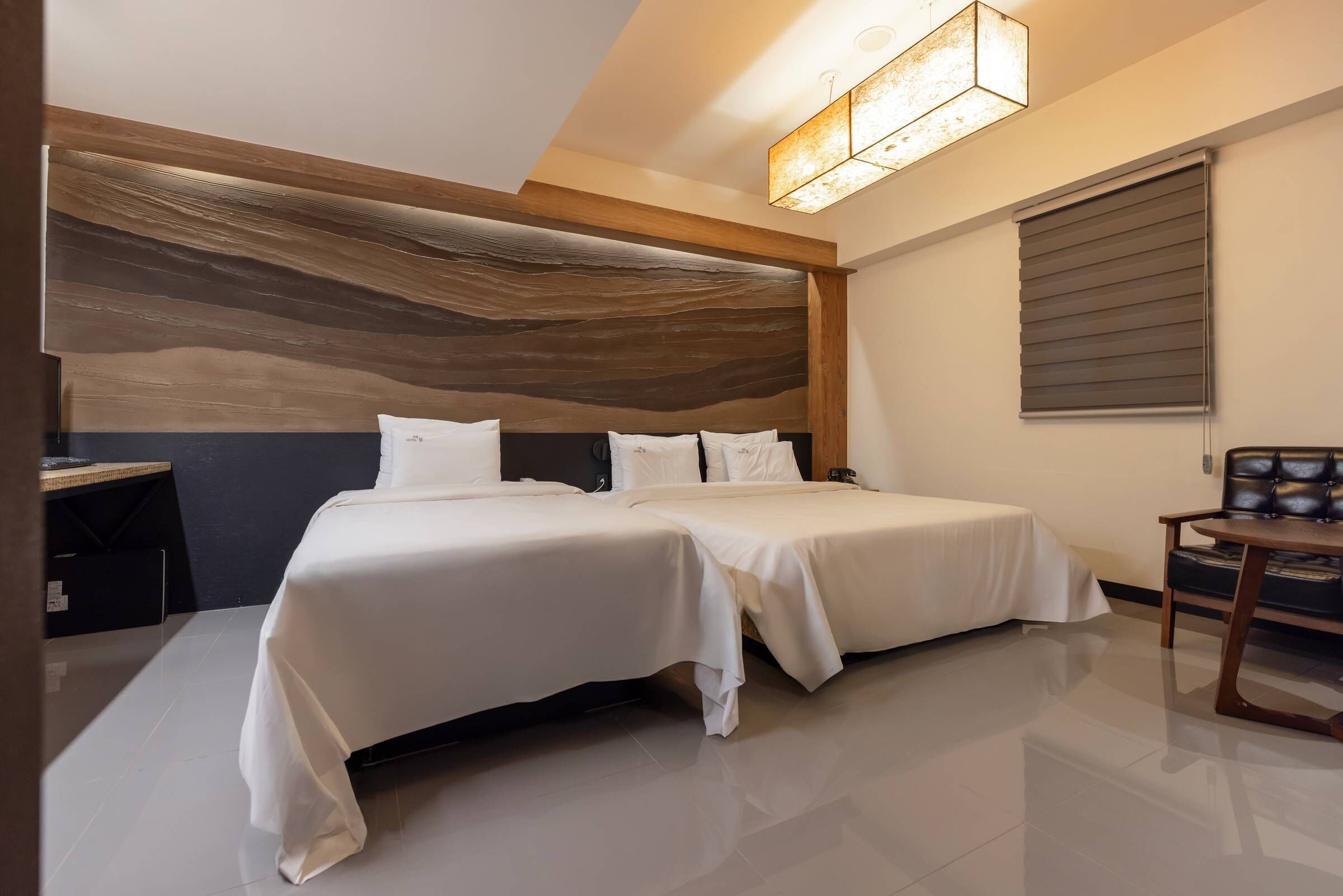 A modern hotel room with a large bed, a desk, and a chair.