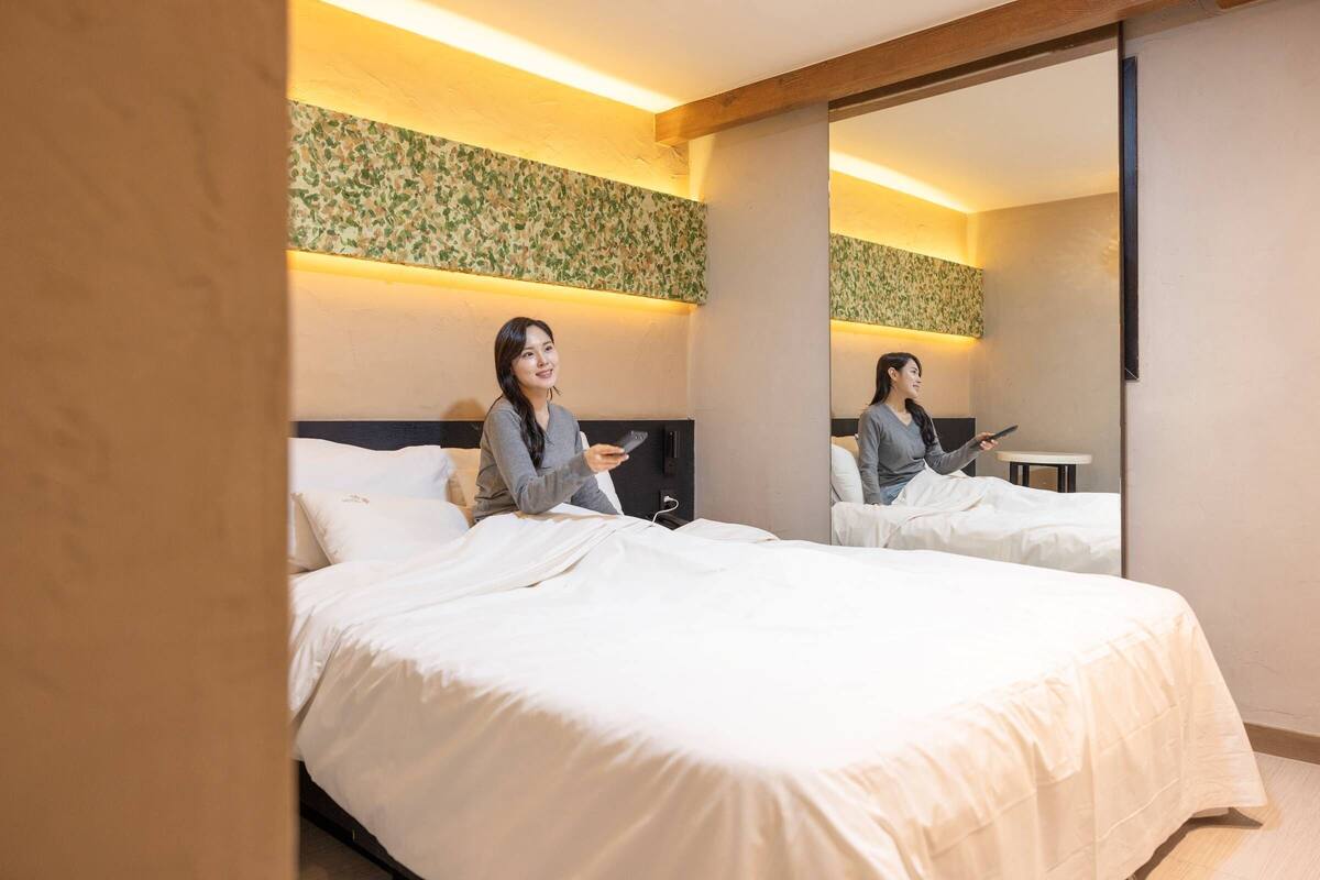 Une chambre d’hôtel avec un grand lit, une table de chevet et un miroir.