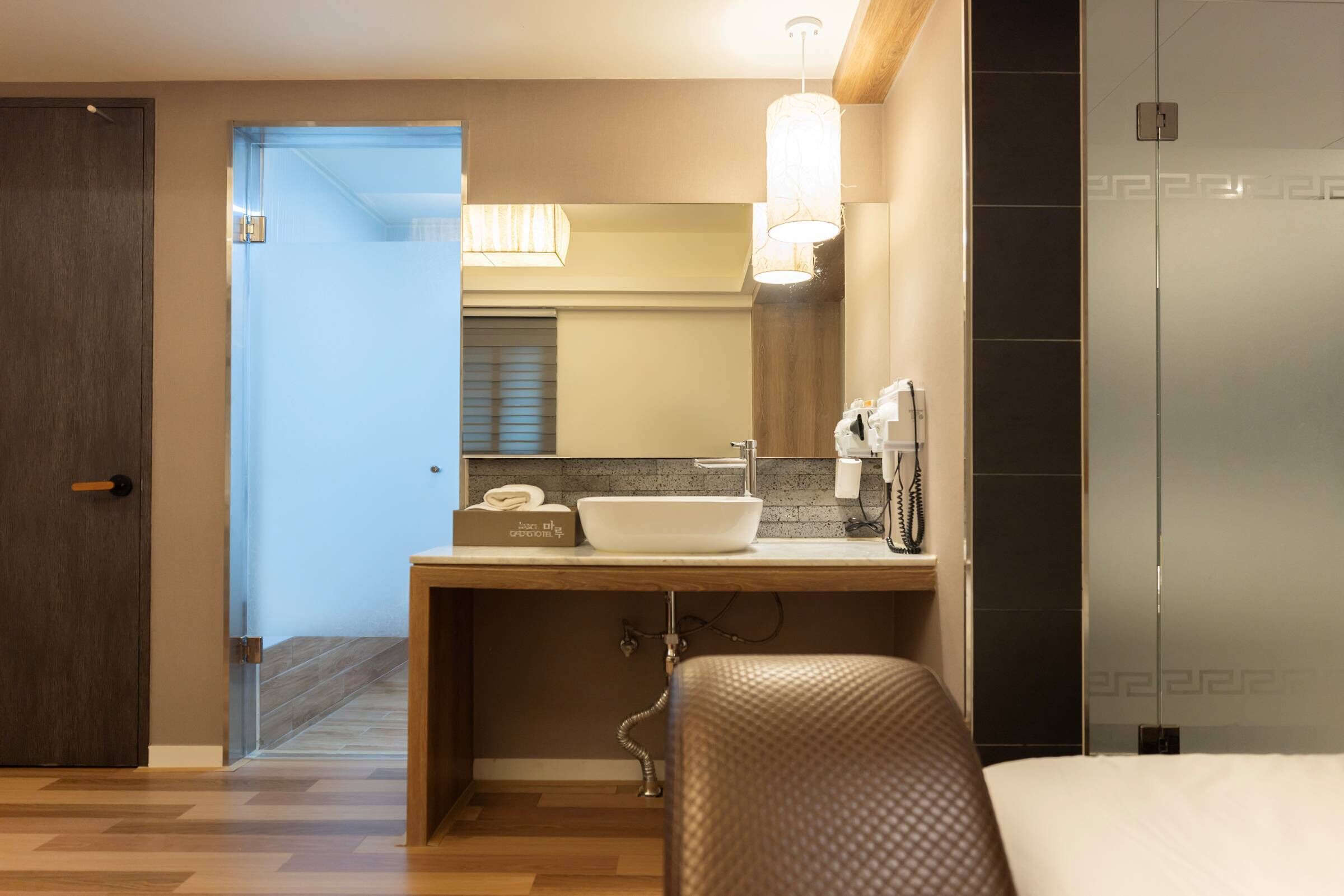 A modern bathroom with a large mirror, a white sink, and a towel dispenser.
