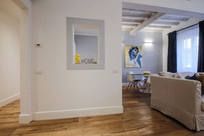 A modern living room with a sofa, a dining area with chairs and a table, and a kitchen in the background.