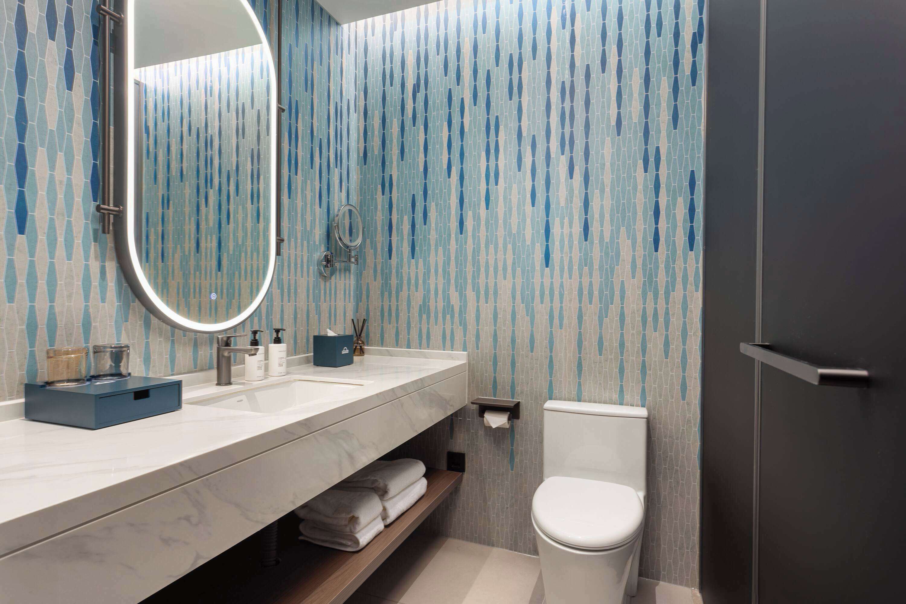 Un baño moderno con tocador de mármol, inodoro y zona de ducha.