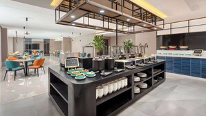 A modern hotel dining area with a buffet setup, seating arrangements, and a kitchen in the background. - Days Inn by Wyndham Xi'an Yanliang (Xi'an)