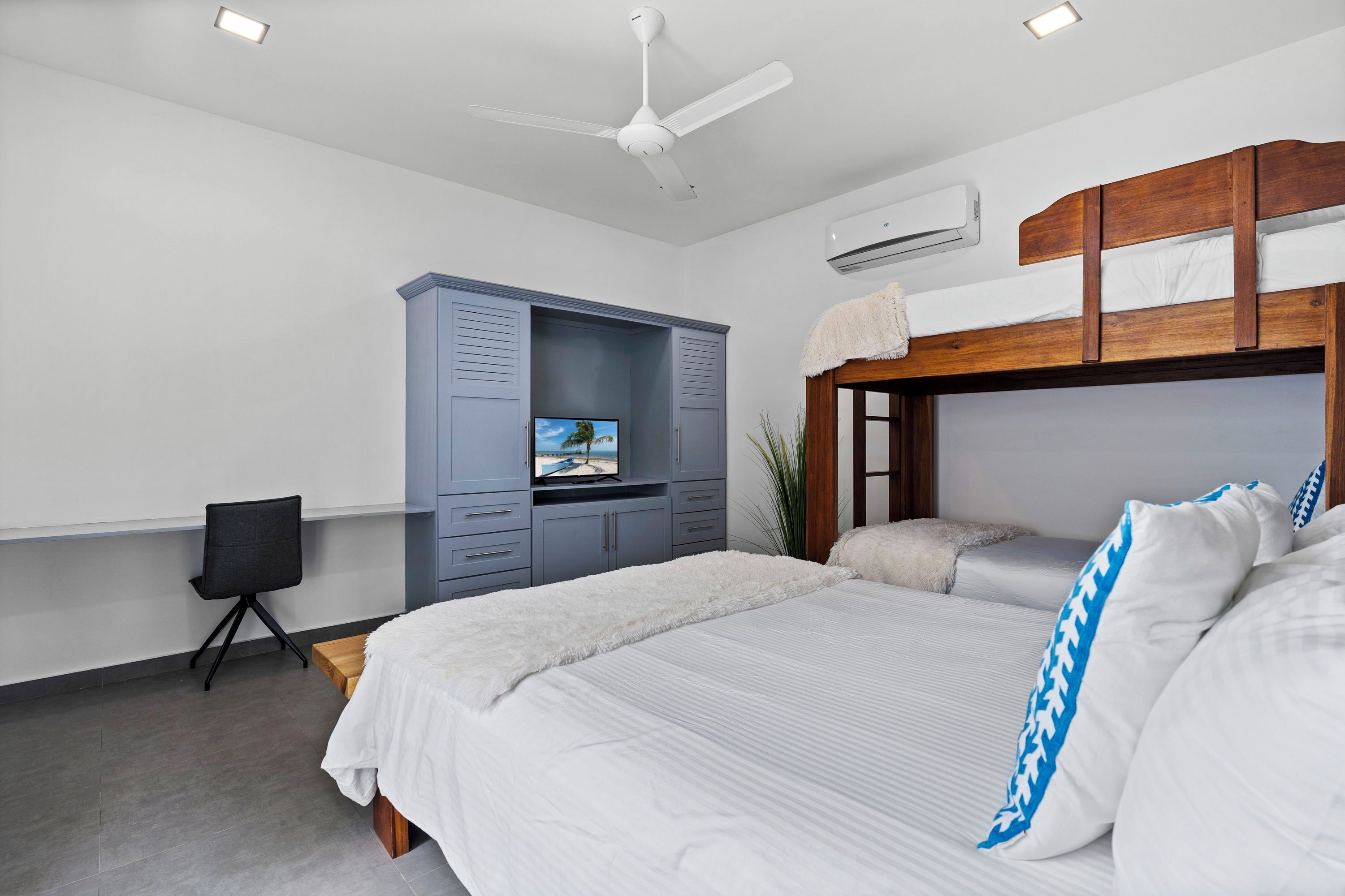 Une chambre moderne avec un lit, un bureau, une chaise et un ventilateur de plafond.