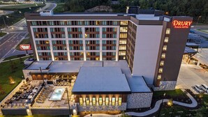Ein Drury Plaza Hotel mit Pool auf dem Dach, Außenbereich mit Sitzgelegenheiten und einer gut beleuchteten Fassade.