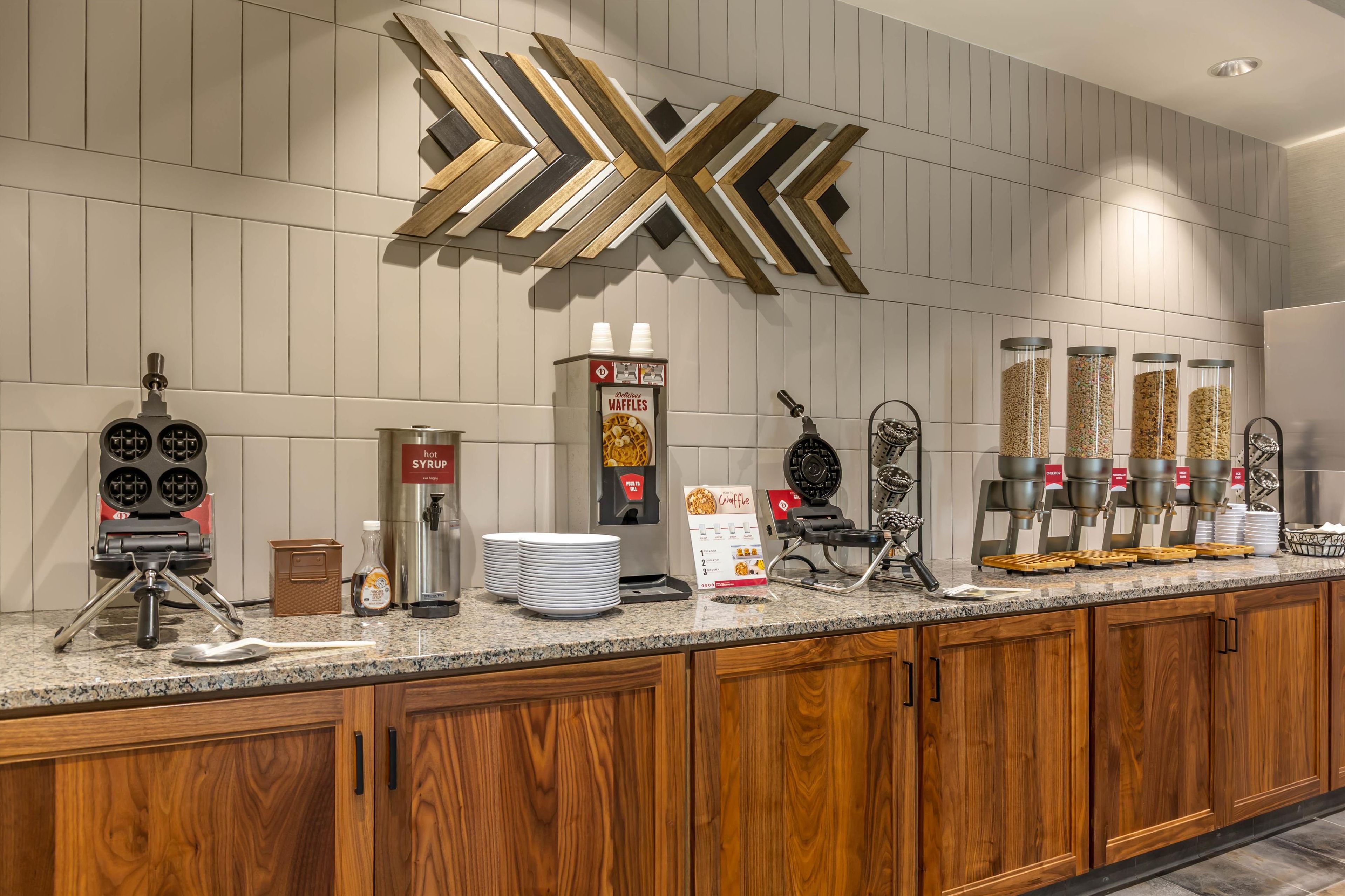 A breakfast bar with waffle makers, syrup dispensers, and waffle containers.