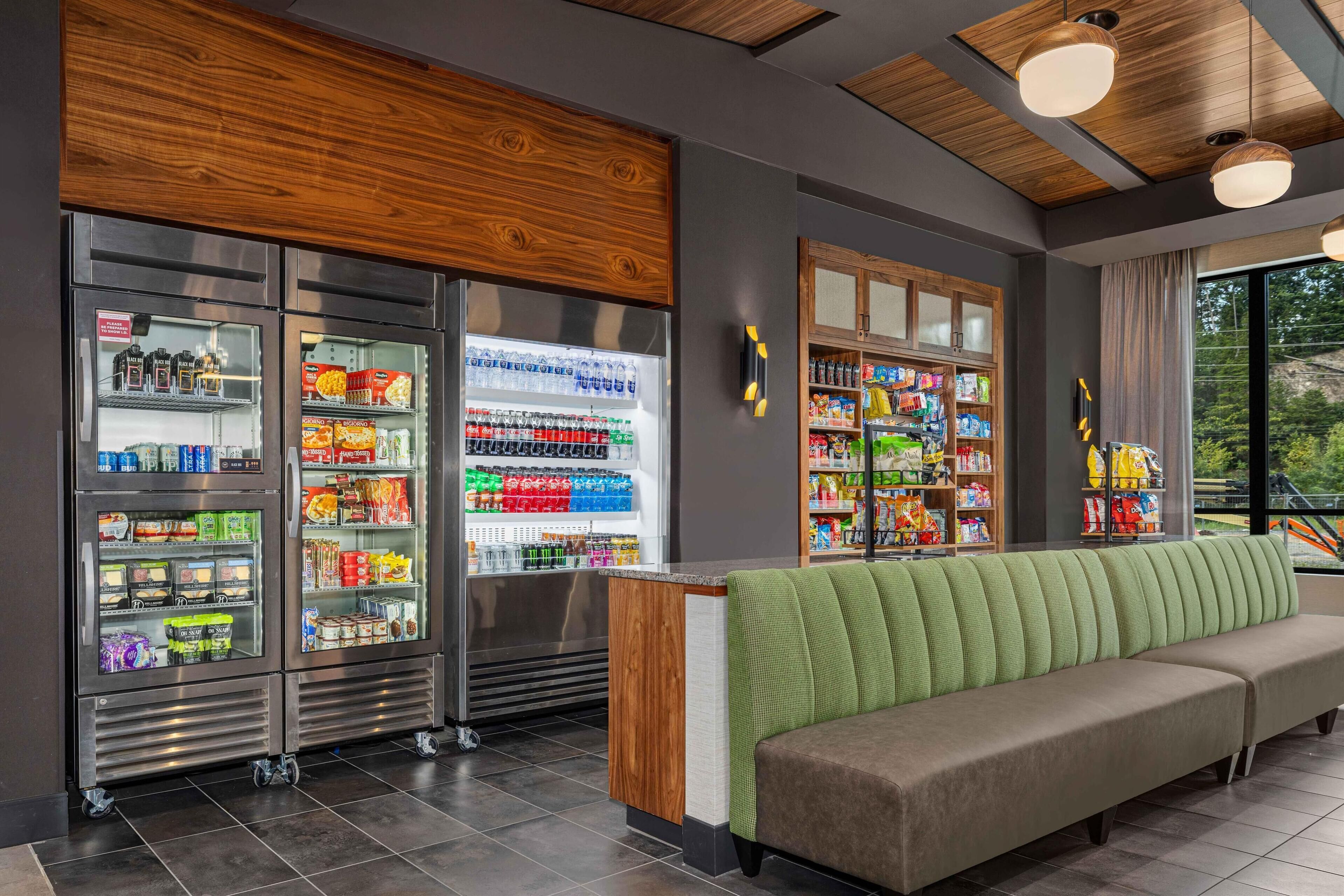A modern interior with vending machines, a green cushioned bench, and a view of the outdoors.