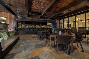 Un moderno espacio de bar con asientos y chimenea de piedra.