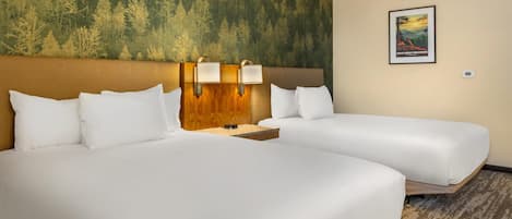 A hotel room with two beds, a headboard with wall-mounted lamps, a poster on the wall, and a carpeted floor.