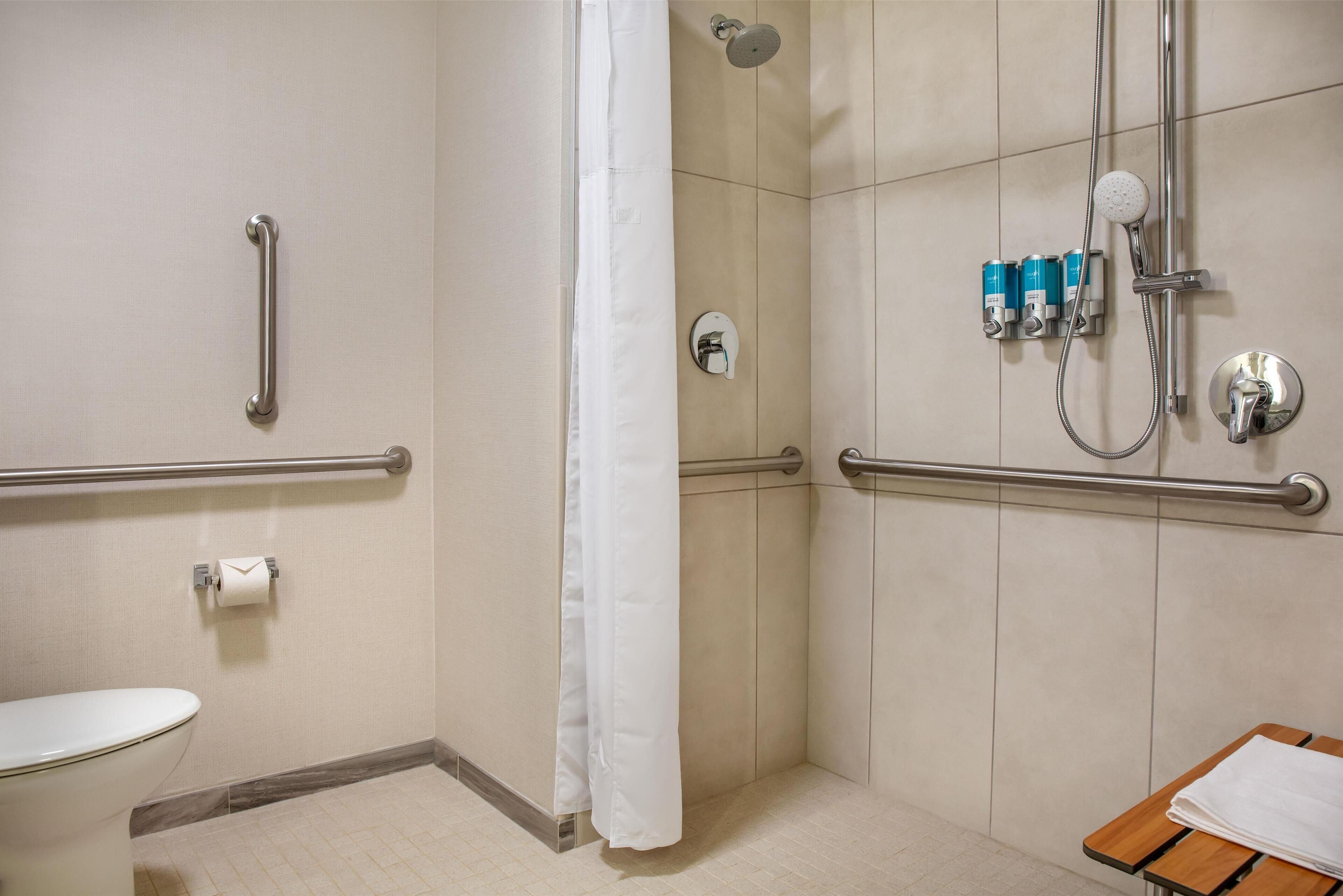 Une salle de bain avec une douche, des toilettes et un banc.