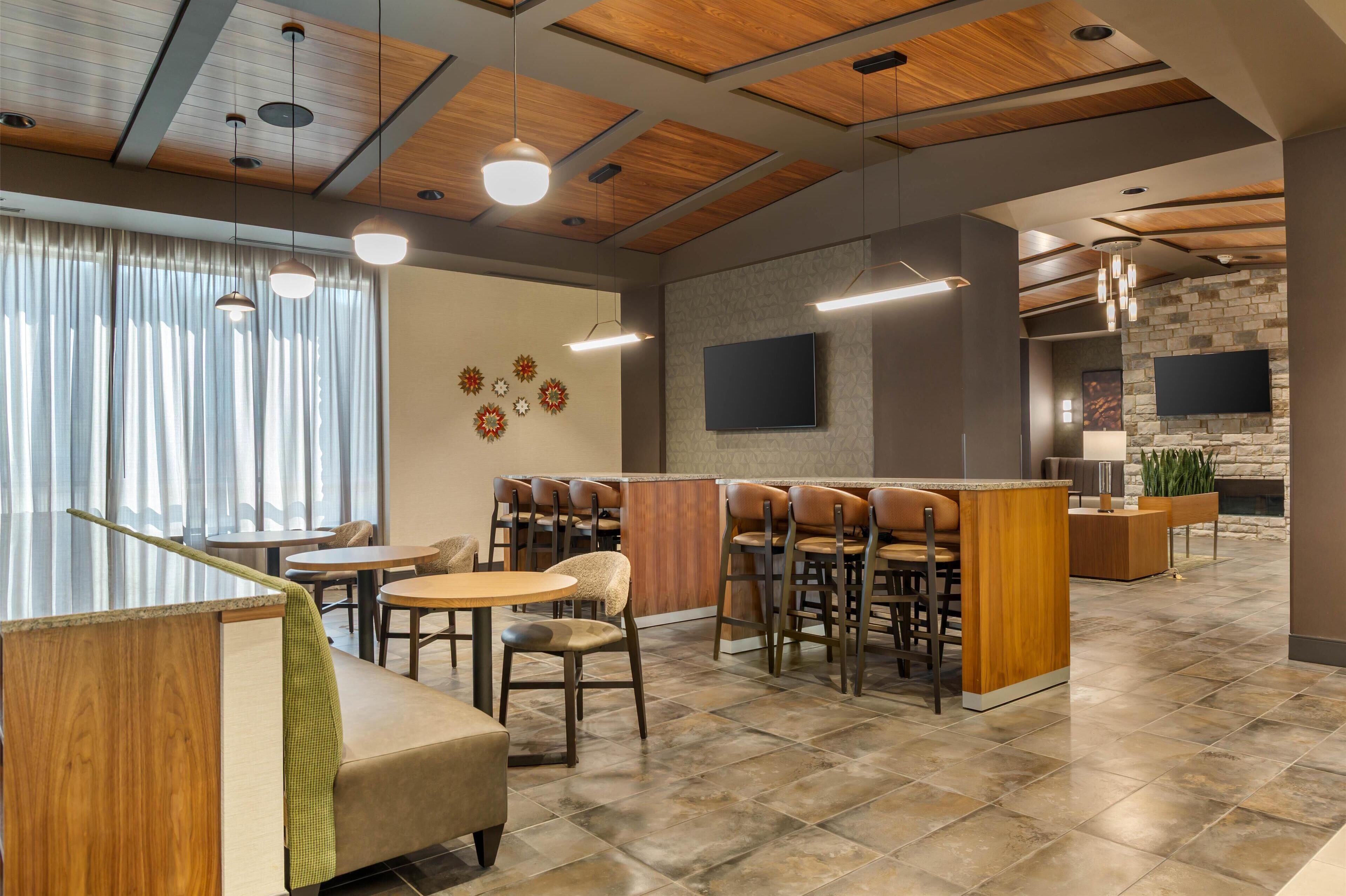 Um restaurante moderno com área de bar, teto de madeira e parede de pedra.