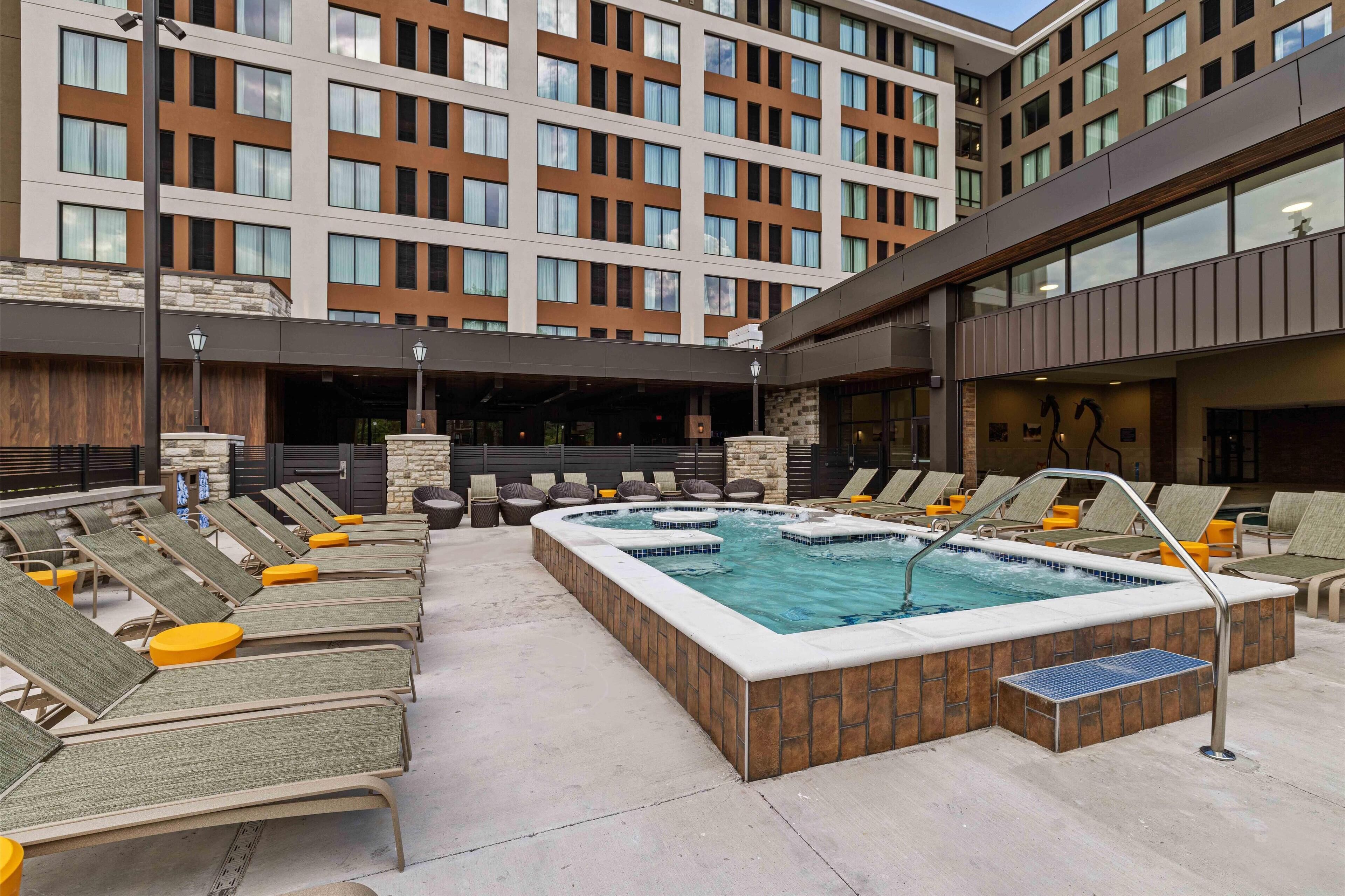 A rooftop pool area with lounge chairs and a hot tub.