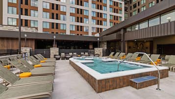Un área de piscina en la azotea con sillones de descanso y un jacuzzi.