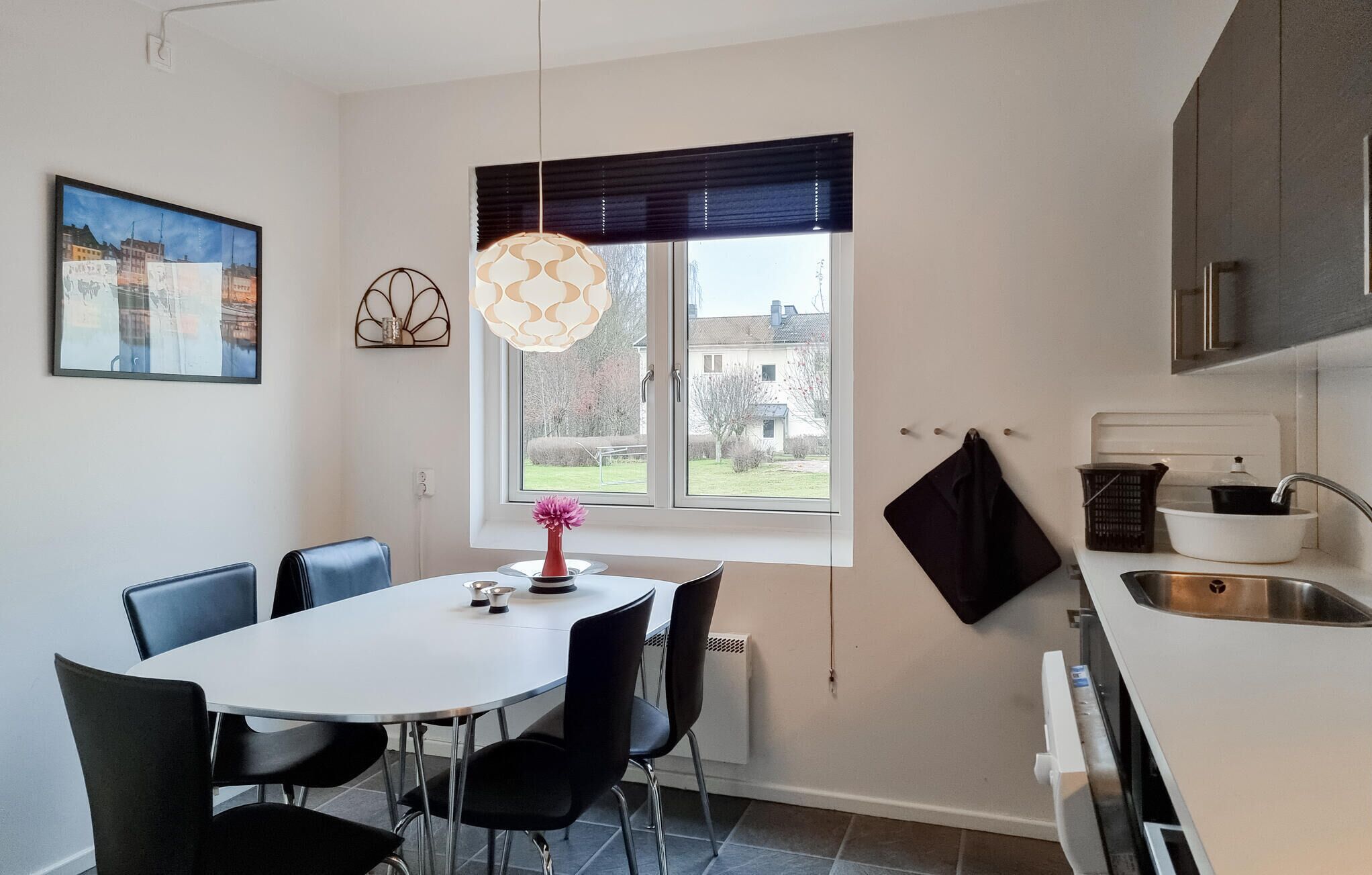 Cozinha moderna com mesa de jantar, cadeiras, luminária pendente, janela com vista e pia.