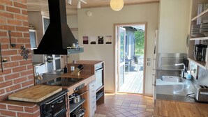 Una cocina moderna con pared de ladrillo, hornos empotrados, una isla grande y vistas a una terraza exterior.