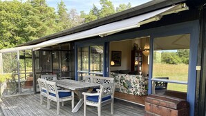 Un espacio al aire libre cubierto con una mesa, sillas, un sofá y vistas al exterior.